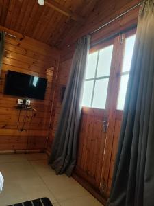 um quarto com uma televisão e uma janela com cortinas em Seawood beach front resort em Morjim