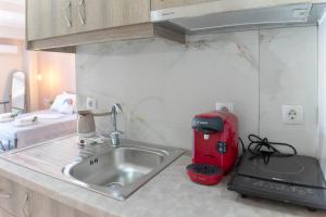 um balcão de cozinha com um lavatório e um aparelho vermelho em Levanda Luxury Studios Apartments em Nydri