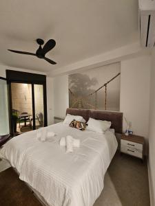 a bedroom with a large white bed with a ceiling fan at צ'יל ורוגע עם ג'קוזי וגינה פרטית in Bayit Wegan