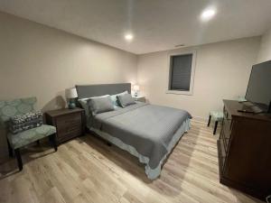 um quarto com uma cama, uma cadeira e uma televisão em The Hamilton House Family Home em Omaha