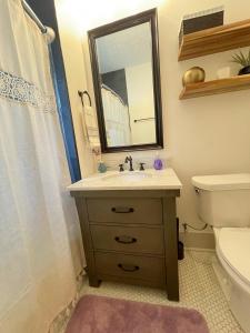 a bathroom with a sink and a toilet and a mirror at The Hamilton House Family Home in Omaha