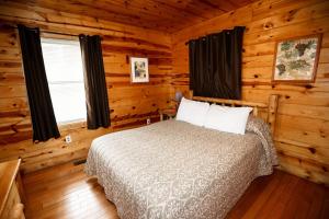 ein Schlafzimmer mit einem Bett in einem Blockhaus in der Unterkunft The Cabins at Pine Haven - Beckley in Beaver