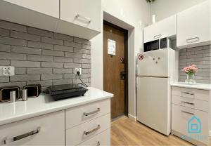 a kitchen with white cabinets and a brick wall at Monroe Room in Gdańsk