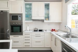 una cocina con armarios blancos y electrodomésticos de acero inoxidable en BN04 Central Playa del Ingles by VillaGranCanaria, en Playa del Inglés