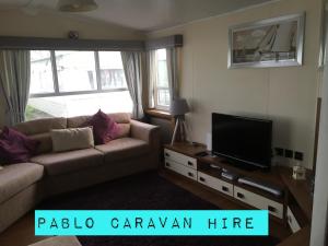 a living room with a couch and a flat screen tv at 3 Bedroom 8 Berth Caravan Towyn in Rhyl