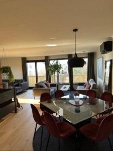een woonkamer met een glazen tafel en stoelen bij Newly Renovated Centrum House with Large Balcony in Haugesund