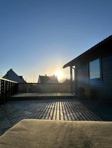 una casa con il sole che tramonta dietro una recinzione di Newly Renovated Centrum House with Large Balcony a Haugesund