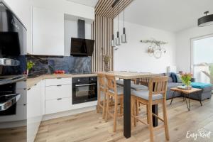 a kitchen with white cabinets and a wooden table and chairs at Dwupoziomowy apartament Grande in Rewal