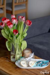 里沃的住宿－Dwupoziomowy apartament Grande，红色花瓶在桌子上,上面有盘子