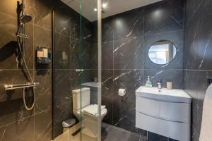 a bathroom with a shower and a toilet and a sink at Katolondonhaus in Mitcham
