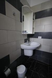 W łazience znajduje się umywalka, toaleta i lustro. w obiekcie Fane's Rooms w mieście Himara