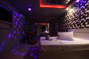 una camera con un letto in una stanza con luci viola di Motel Deslize Limeira 3 a Limeira