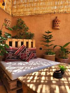 Bett mit Kissen in einem Zimmer mit Pflanzen in der Unterkunft Medina Oasis Hostel in Marrakesch