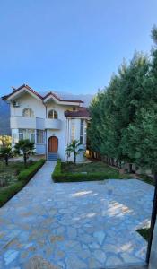 a large white house with a stone driveway at Vila Guri i Atos in Përmet