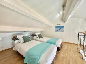 Cet hébergement comprend 2 lits dans une chambre dotée de murs blancs et de parquet. dans l'établissement Le St Julien Terrasse vue mer exceptionnelle, à Menton