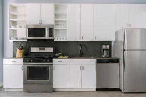 a kitchen with white cabinets and a stainless steel refrigerator at Sonder The Plymouth in Chicago