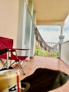 uma varanda com 2 cadeiras vermelhas e uma rede de descanso em Camino Al Cielo em Guayanilla