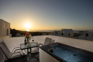 a hot tub on a balcony with a table and chairs at Nastram Suites Oia in Oia