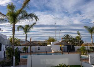 een hek met palmbomen en een zwembad bij Villa Lagarto - Denia El Verger in Denia
