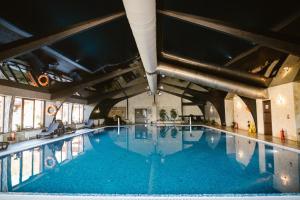 a large swimming pool with blue water in a building at Bellacya Resort & Spa in Sovata