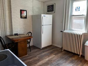 a kitchen with a white refrigerator and a table at Great Gorge Guesthouse - Walk to the Falls, the Casino and all Downtown Restaurants - Across from the Aquarium in Niagara Falls