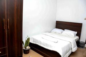 1 cama con sábanas blancas y cabecero de madera en una habitación en FANZMA APARTMENTS, en Abuja