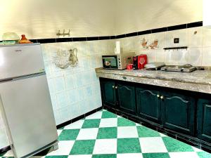 eine Küche mit einem Kühlschrank und einem karierten Boden in der Unterkunft Mini villa in Oujda