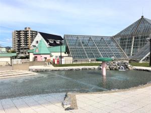 einen Brunnen in einem Teich vor einem großen Gebäude in der Unterkunft Hotel Tetora Yunokawaonsen - Vacation STAY 30541v in Hakodate