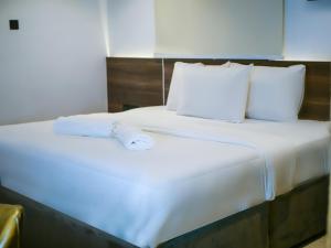 a large white bed with white sheets and pillows at Oliver Twist Hotel in Lagos