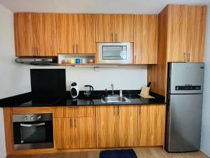 Una cocina con gabinetes de madera y un refrigerador de acero inoxidable. en 1-Bed - Sleeps 4 with City view, en Cagayan de Oro