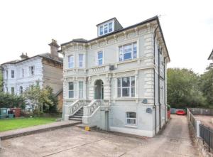 a large white house with a staircase at Cosy 2 bedroom garden flat with parking in Royal Tunbridge Wells