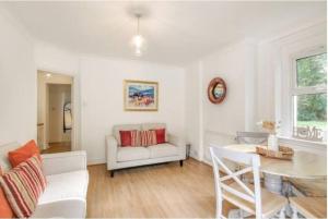 a living room with a white couch and a table at Cosy 2 bedroom garden flat with parking in Royal Tunbridge Wells