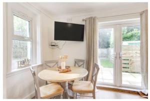 a dining room with a table and chairs and a tv at Cosy 2 bedroom garden flat with parking in Royal Tunbridge Wells