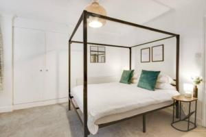 a bedroom with a canopy bed with green pillows at Cosy 2 bedroom garden flat with parking in Royal Tunbridge Wells