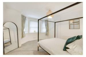 a bedroom with a canopy bed and a mirror at Central 2 bedroom garden flat with free parking in Royal Tunbridge Wells