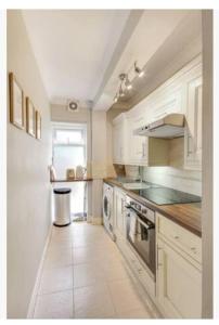 a kitchen with white cabinets and a stove top oven at Central 2 bedroom garden flat with free parking in Royal Tunbridge Wells +6 photos