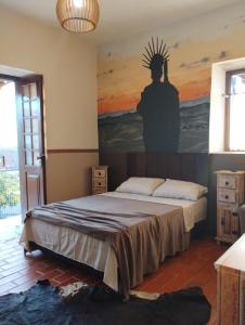 a bedroom with a bed with a painting on the wall at Recanto das Pedras Hospedagem in São Thomé das Letras