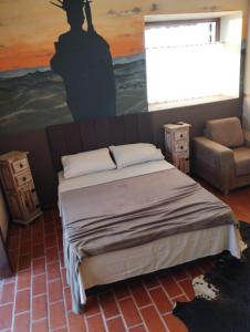 a bedroom with a bed and a painting on the wall at Recanto das Pedras Hospedagem in São Thomé das Letras