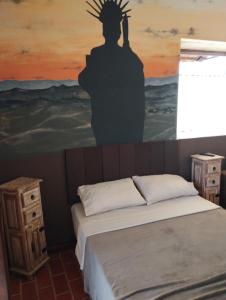 a bedroom with a bed with a painting on the wall at Recanto das Pedras Hospedagem in São Thomé das Letras