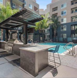 a outdoor kitchen with a grill and a chair next to a pool at Chic Luxury Condo near Hollywood in Glendale