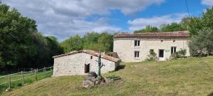 Un gîte en Charente, gîte 4 étoiles في Roullet-Saint-Estèphe: مبنى حجري قديم على تلة عشبية