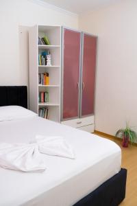 ALBJONA GUESTHOUSE TIRANA في تيرانا: سرير أبيض في غرفة مع رف كتاب