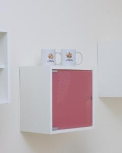 a white cabinet with two mugs and a red door at ALBJONA GUESTHOUSE TIRANA in Tirana