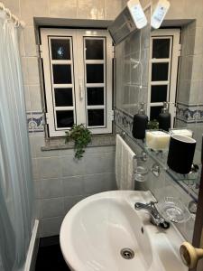 ein Bad mit einem Waschbecken und einem Spiegel in der Unterkunft White House in Piódão