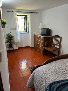 ein Schlafzimmer mit einem Bett, einem TV und einem Stuhl in der Unterkunft White House in Piódão