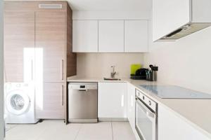 a kitchen with white cabinets and a washer and dryer at VillaHeLena in Orihuela Costa