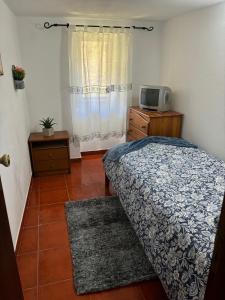a small bedroom with a bed and a tv at White House in Piódão