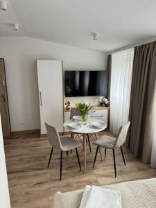 a living room with a table and chairs and a television at Apartamenty Misdroy Parking Gratis 250 m od plaży in Międzyzdroje