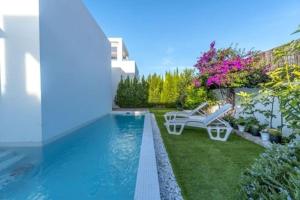 a backyard with a swimming pool with chairs and flowers at VillaHeLena in Orihuela Costa