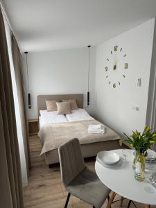 a bedroom with a bed and a table and a clock at Apartamenty Misdroy Parking Gratis 250 m od plaży in Międzyzdroje